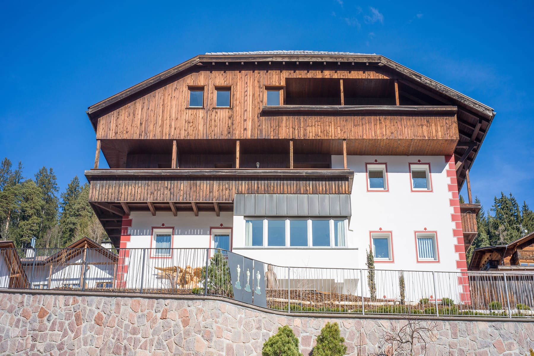 Foto der Frontalansicht von Haus Scurcià mit zum Teil sichtbaren Skulpturen im Garten