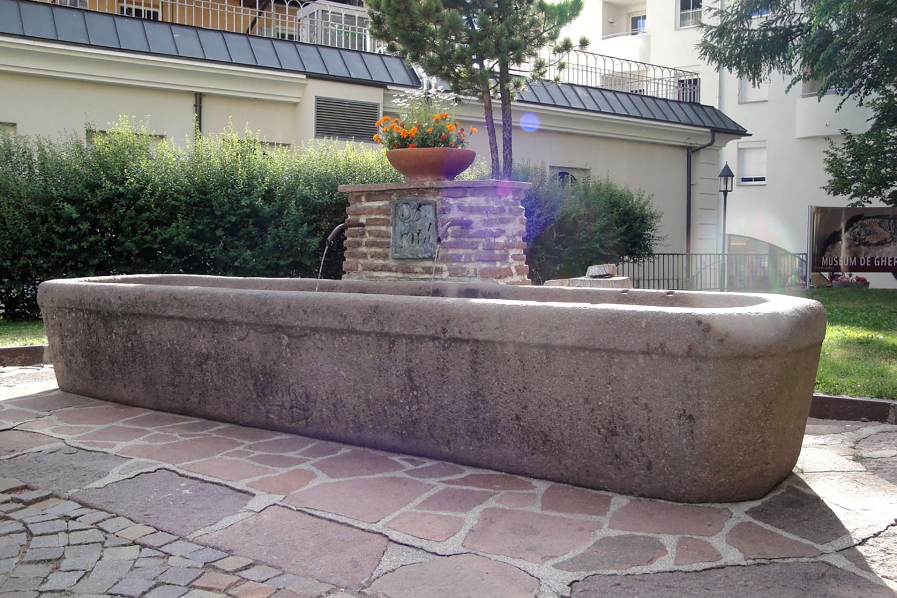 Langgezogener, gehauener Porphyrtrog mit Abrundung und Wappen an der Vorderseite