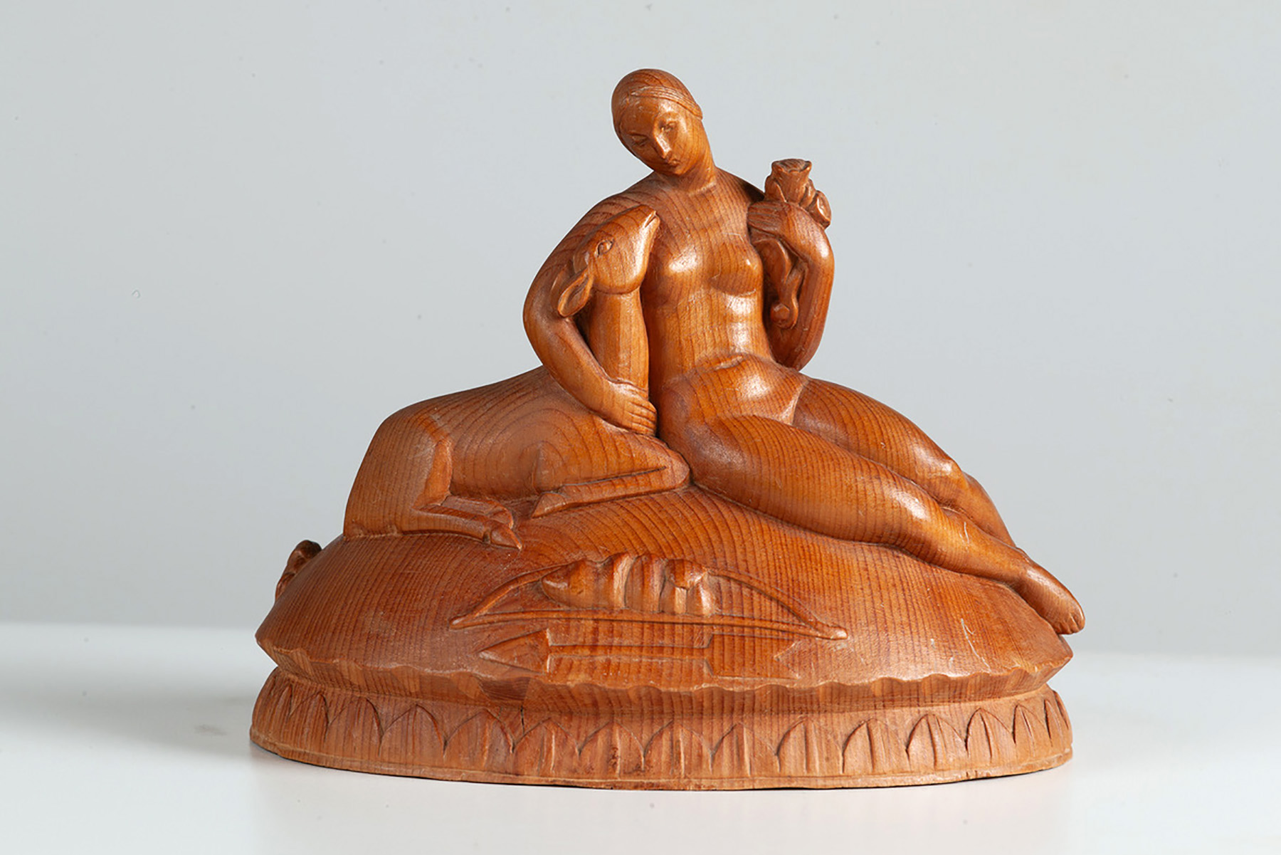 Geschnitzte Skulptur der halb liegenden, nackten Jagdgöttin Diana mit einem Reh im rechten Arm und einem Blumenstrauß im linken