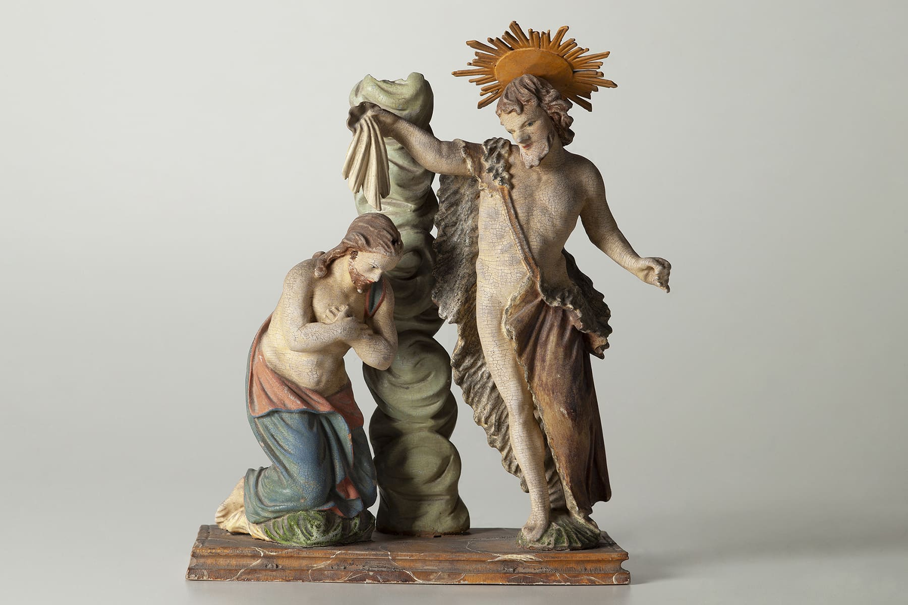 Skulptur der Taufe Jesu, wobei Johannes der Täufer eine Schale mit Wasser über dem Kopf des knienden Christi leert