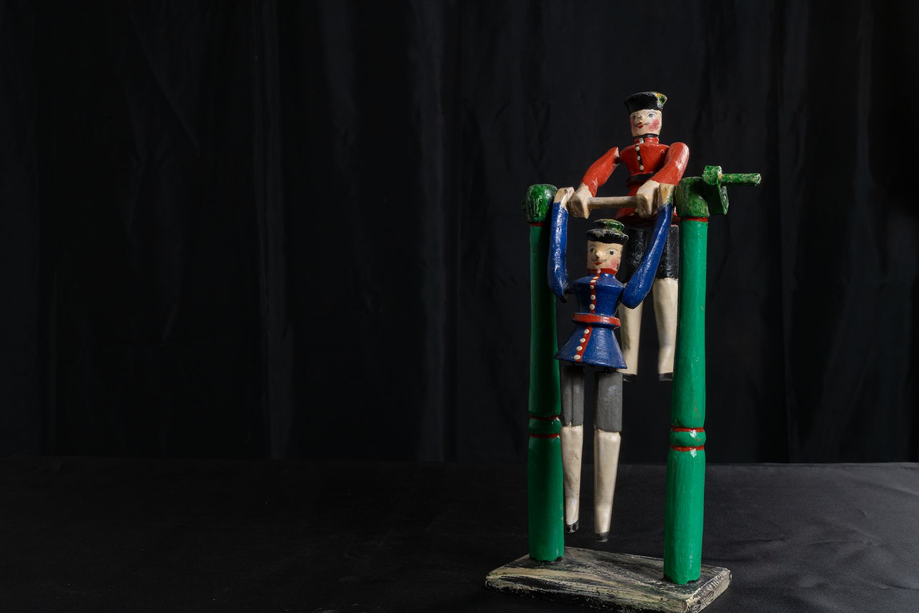 Geschnitztes und bemaltes Spielzeug zweier Turner am Reck, die sich mit der Kurbel bewegen lassen