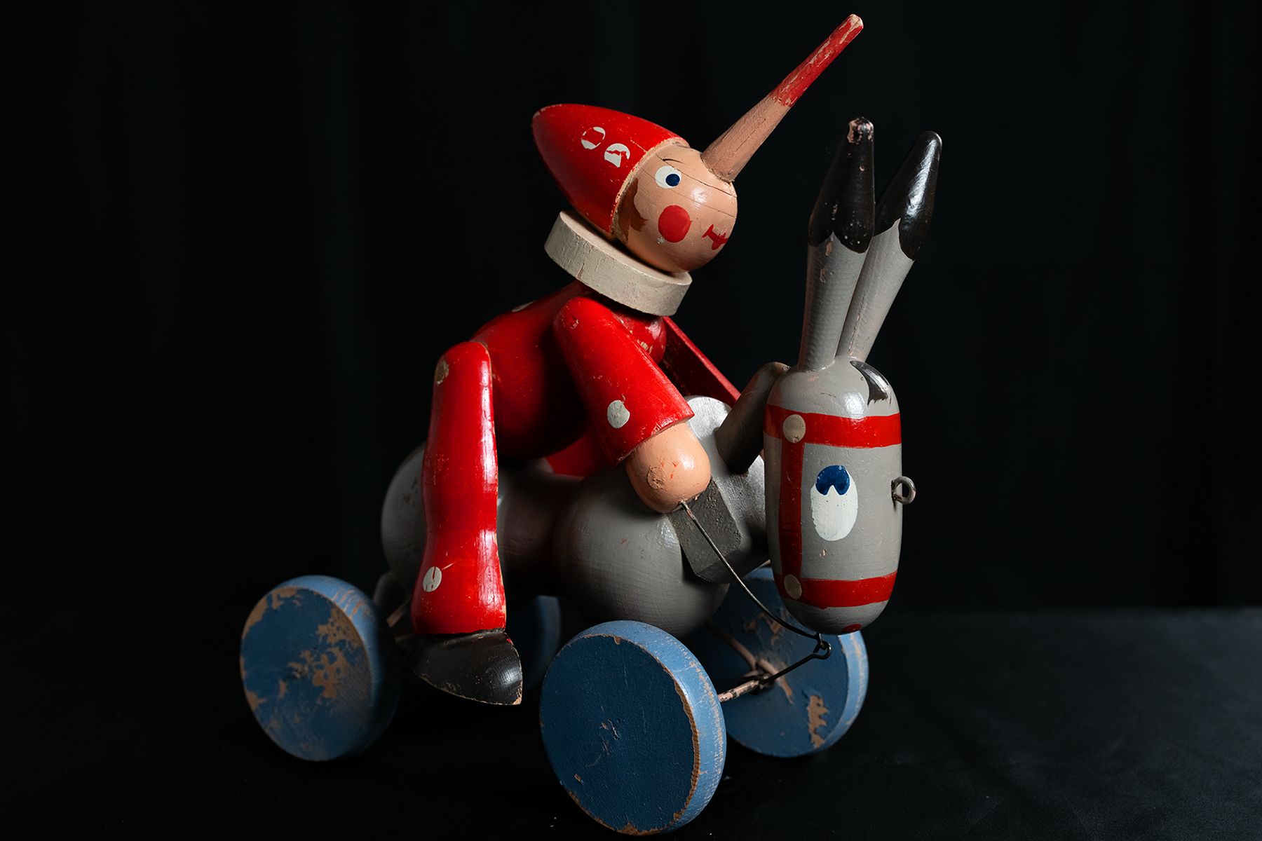Gedrechselt und bemalter Pinocchio reitend auf einem Esel mit vier Rädern