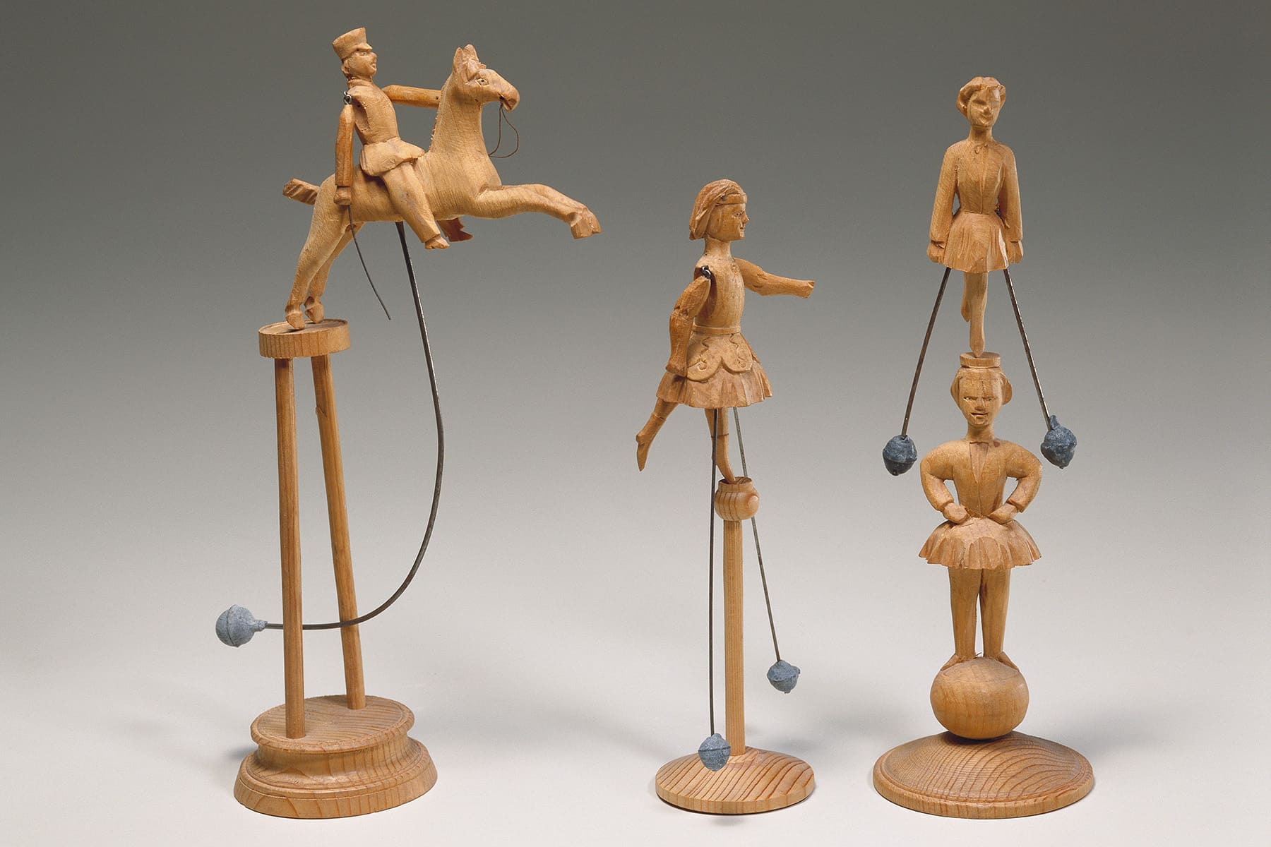 Pferd und Reiter sind lose auf ein Podest aufgesetzt, ein Bleigewicht hält sie im Gleichgewicht. Sobald die Figur angestoßen wird, schwingt sie, wird aber auf der Säule gehalten. Nach demselben Prinzip funktioniert auch die Akrobatin, die sich – einmal angestoßen – im Kreis dreht. Wer diese Spielzeuge geschaffen hat, kann nicht eruiert werden, so blieben die Schnitzerinnen und Schnitzer anonym.
