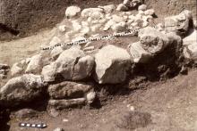 Im Vordergrund größere Steinblöcke als Reste der Mauer eines rätischen Hauses aus der mittleren Eisenzeit, dahinter kleinere Steine des gepflasterten Hauseingangs, ausgegraben 1977 unterhalb des Col de Flam Hofes.
