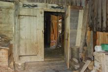 Zwei einander zugewandte schwarze Schlangen am Sturzbalken des Stadeltors von Mëune