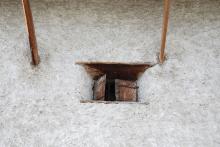 Über dem kleinen Fenster des Untergeschosses sind die Stützen des darüberliegenden Wohngeschosses aus Holz.