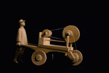 Spielzeug eines Scherenschleifers, dessen Beine sich mit dem rollenden Wagen bewegen