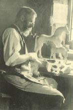 Grödner Pferdeschnitzer Josef Stuflesser beim Schnitzen auf dem Hof Pradel Dessot, Aufnahme von ca. 1906