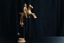 Reiter und Pferd aus Naturholz lose auf einem Podest aufgesetzt und durch ein Bleigewicht in Balance gehalten