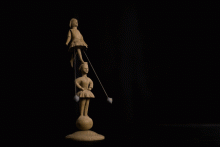 Akrobatin, die auf Zehenspitzen auf dem Kopf einer zweiten steht und beim Anstoßen der zwei Bleigewichte vor und zurück schwingt